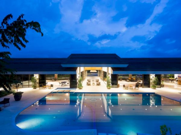 A large, modern building with expansive exterior lighting and a reflecting pool in front, set against a twilight sky. The sentence ends here.