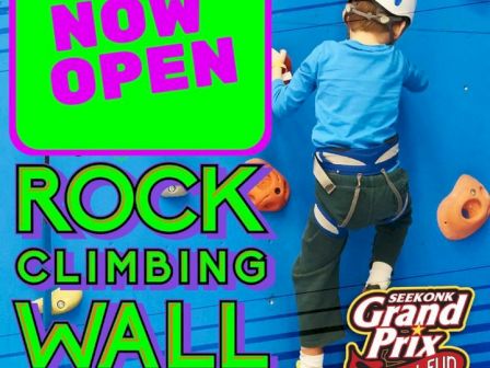 Kid climbing a rock wall; text highlights the grand opening of the rock climbing wall at Seekonk Grand Prix Family Fun Center.