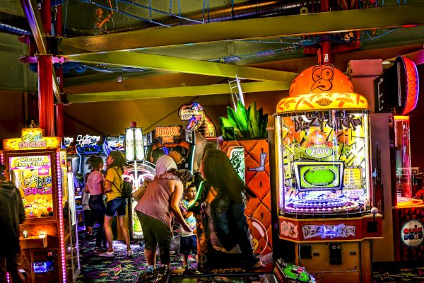 People enjoying arcade games in a vibrant, colorful gaming space, with various machines and lively décor.