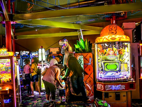 People enjoying arcade games in a vibrant, colorful gaming space, with various machines and lively décor.