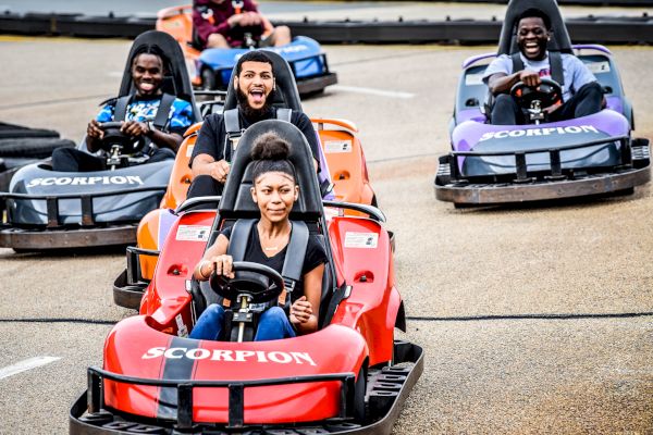 People are enjoying go-kart racing, each driving a kart labeled 