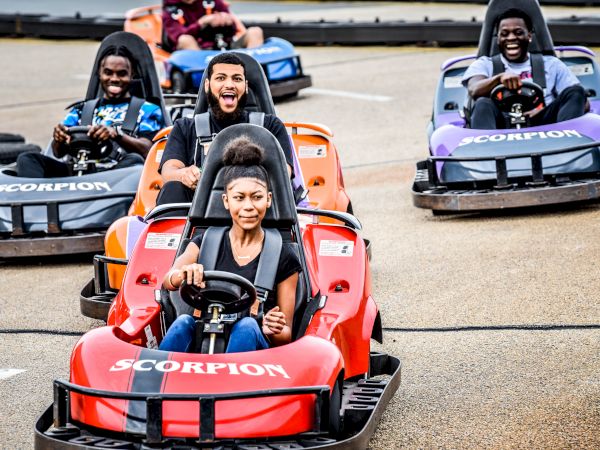 People are enjoying go-kart racing, each driving a kart labeled "Scorpion." Everyone seems to be having fun on the track.