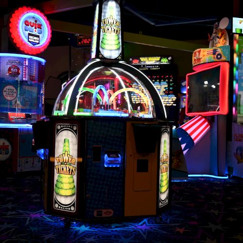 An image of a colorful arcade featuring various game machines, bright neon lights, and vibrant designs, creating a lively entertainment atmosphere.