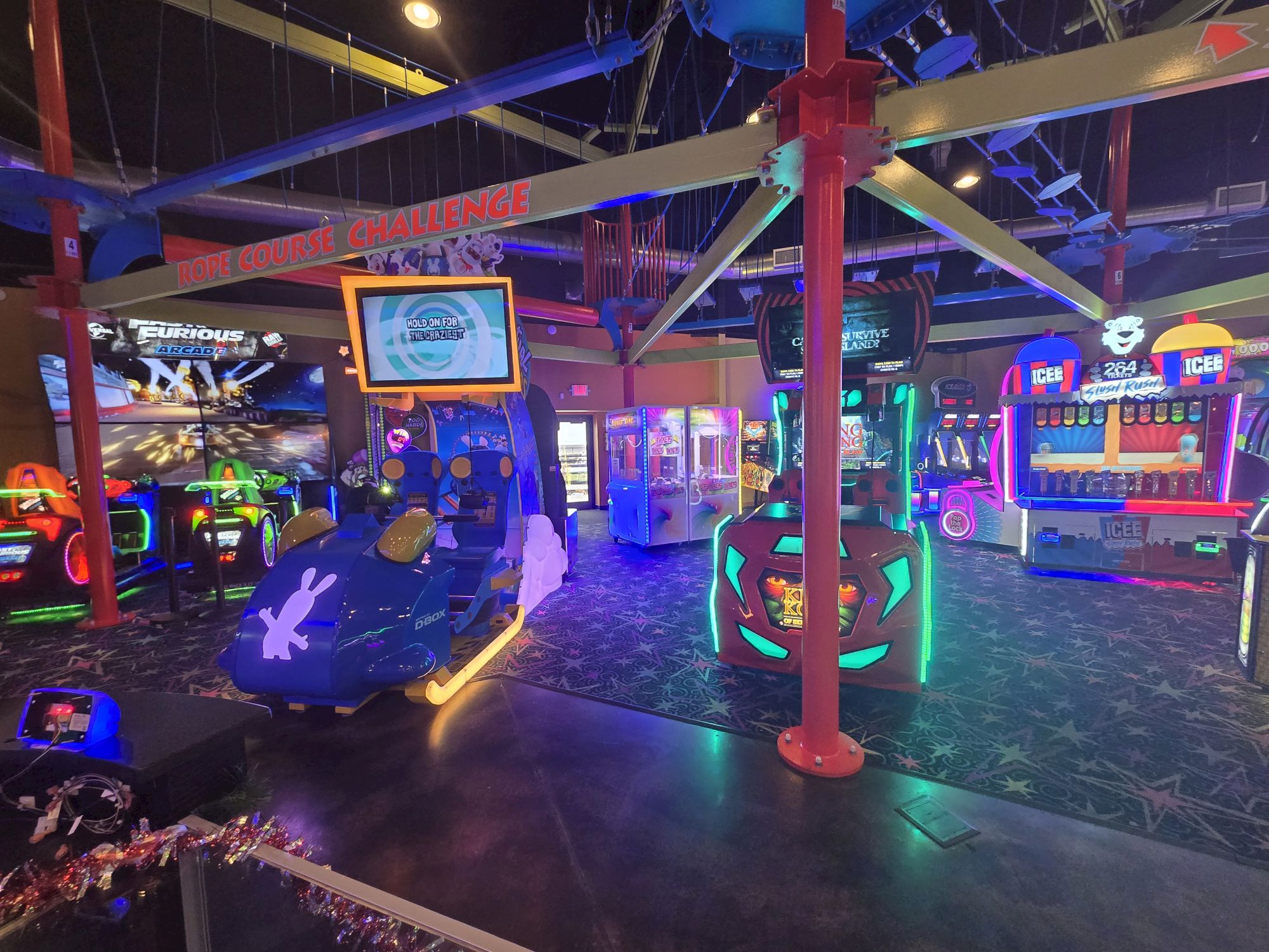 A neon-lit arcade with bumper cars, glowing panels, and vibrant screens under a starburst ceiling, kids ride while colorful lights flicker.