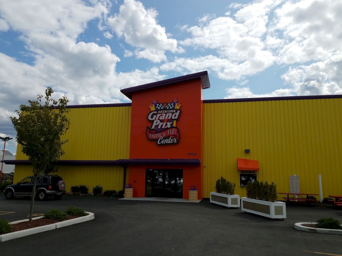 The image shows the exterior of a bright yellow and orange building labeled "Grand Prix Family Fun Center."