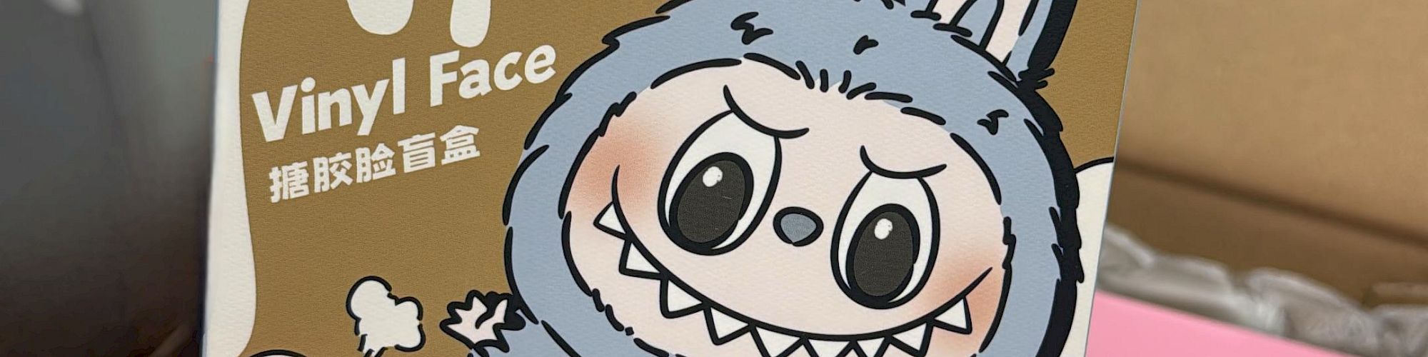 A cartoon &ldquo;Exciting Macaroon&rdquo; box featuring a blue bunny monster with big teeth, bold text, and playful smash graphics on a display box.