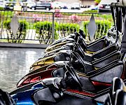 Close-up of a black-and-gold sport motorcycle parked in a street, with a railing and blooming greenery in the background.