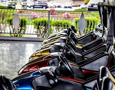 Close-up of a black-and-gold sport motorcycle parked in a street, with a railing and blooming greenery in the background.