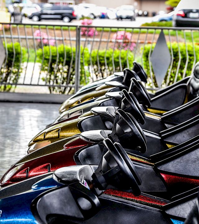 Close-up of a black-and-gold sport motorcycle parked in a street, with a railing and blooming greenery in the background.