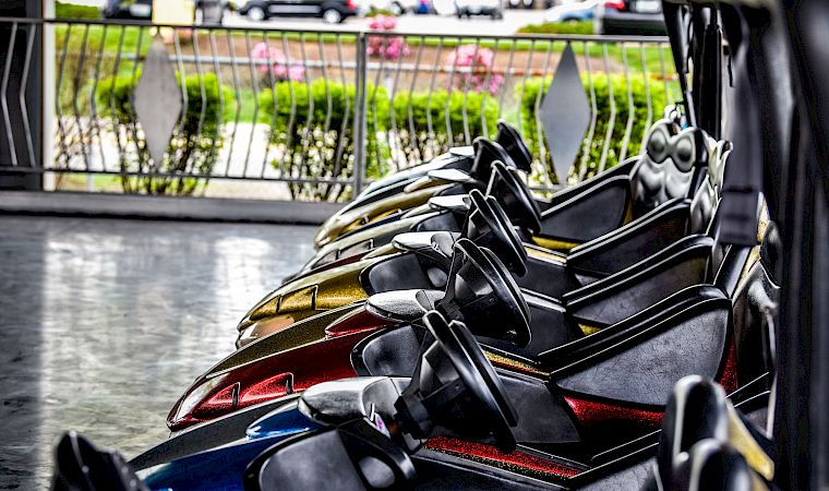 Close-up of a black-and-gold sport motorcycle parked in a street, with a railing and blooming greenery in the background.