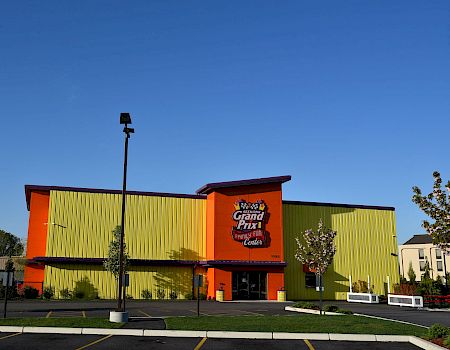 An orange-and-green Family Fun Center building with a “Seekonk Grand Prix” sign under a blue sky.