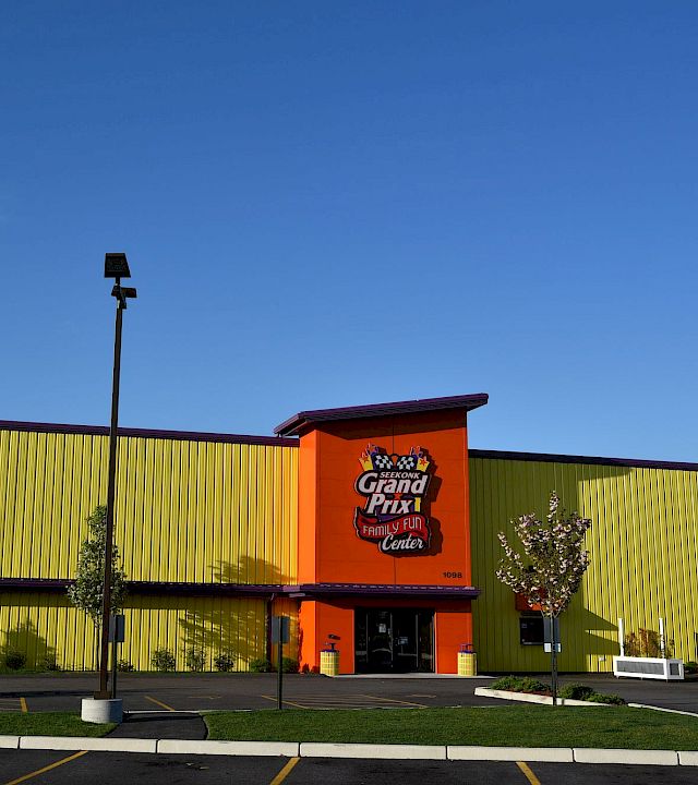 An orange-and-green Family Fun Center building with a “Seekonk Grand Prix” sign under a blue sky.
