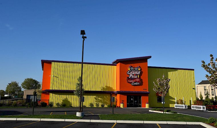 An orange-and-green Family Fun Center building with a “Seekonk Grand Prix” sign under a blue sky.